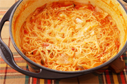 しめには、鍋パスタ！　鍋から大きな具は取り出し、ゆでたカッペリーニを加えてよくからめ、粉チーズをたっぷりふります。粉チーズがしっとり溶けたところがおいしい。