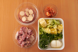鶏肉はフォークで皮をつついて一口大に切り、塩、こしょうをふる。キャベツは大きめのざく切り、玉ねぎは幅1センチのくし形に切る。ピーマンはへたと種を除いて縦6等分に切る。さつまいもは幅1センチの輪切りにし、水にさらす。白菜キムチは食べやすく切る。