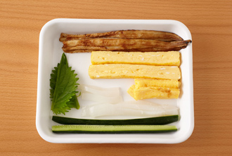 厚焼き卵を作る。卵を溶きほぐし、だし汁、砂糖、塩を加えて混ぜ、卵焼き器で焼いて棒状に切る。あなごは幅1センチに切り、フライパンでさっと焼く。きゅうりは縦半分に切る。いかも幅1センチに細長く切る。青じそは半分に切る。