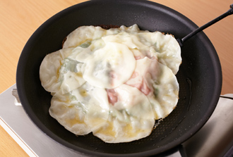 水1/4カップ（分量外）を回し入れて中火にかける。ふたをして5分ほど蒸し焼きにする。水気がなくなり、底に焼き色がついたらごま油を回し入れ、フライ返しで裏返す。ふたをせずに3分ほど焼き、もう一度裏返して焼き目をつけたらでき上がり。皿に盛り、食べやすく切って万能ねぎを散らす。ポン酢しょうゆをつけて食べる。