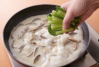 あさりの口が開いたら豆乳を加えて強火にし、煮立ったら小松菜を加える。中火にして2分ほど煮たら塩を加えて器に盛り、バターをのせる。