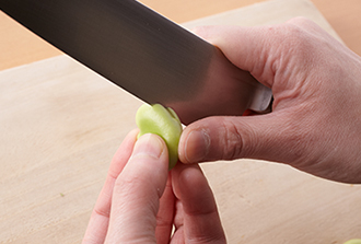 そら豆は黒い部分に浅く切り込みを入れ、そこから薄皮をむく。高菜漬けは粗みじん切りにする。豚肉は厚さ1センチに切り、筋切りをして塩をふる。