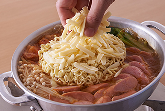 具に火が通ったらインスタントラーメンを入れてチーズをのせ、麺に火が通るまで3分ほど煮る。