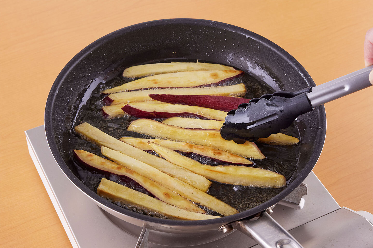 フライパンにさつまいもと揚げ油を入れて中火にかける。5分ほど揚げ焼きにし、上下を返してさらに3分ほど揚げ焼きにする。最後に強火にして1分ほど転がしながら揚げ焼きにし、取り出して油をきる。粉チーズと赤しそふりかけをかけてまぶす。