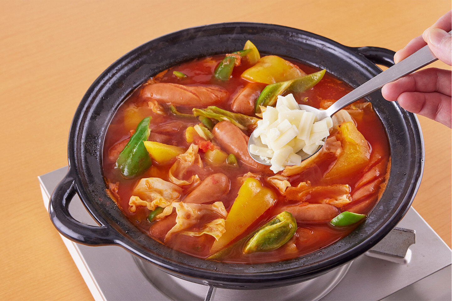 ピーマンを加えてサッと煮て、ピザ用チーズを散らして加える。ふたをしてチーズを溶かす。チーズがほどよく溶けたら火を止めてにんにくをのせて完成。混ぜながら、具と汁を取り分けて食べる。